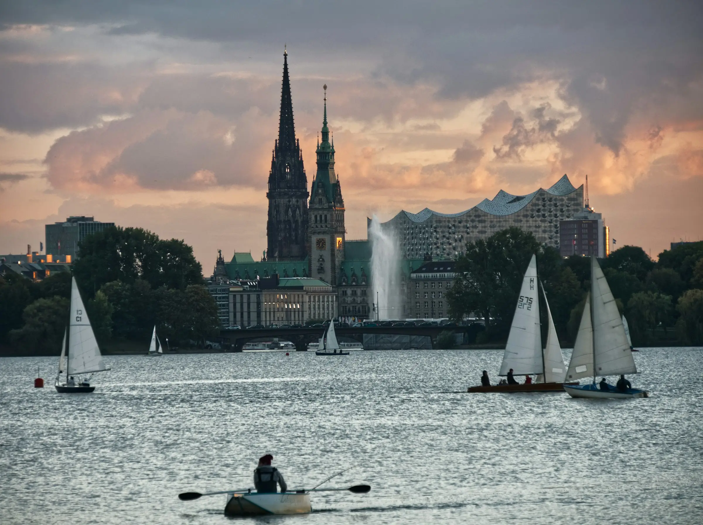Hamburg’da Alster Gölü’nde yelkenliler ve şehir silueti